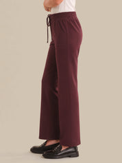 Maroon pants worn by a person on a beige background