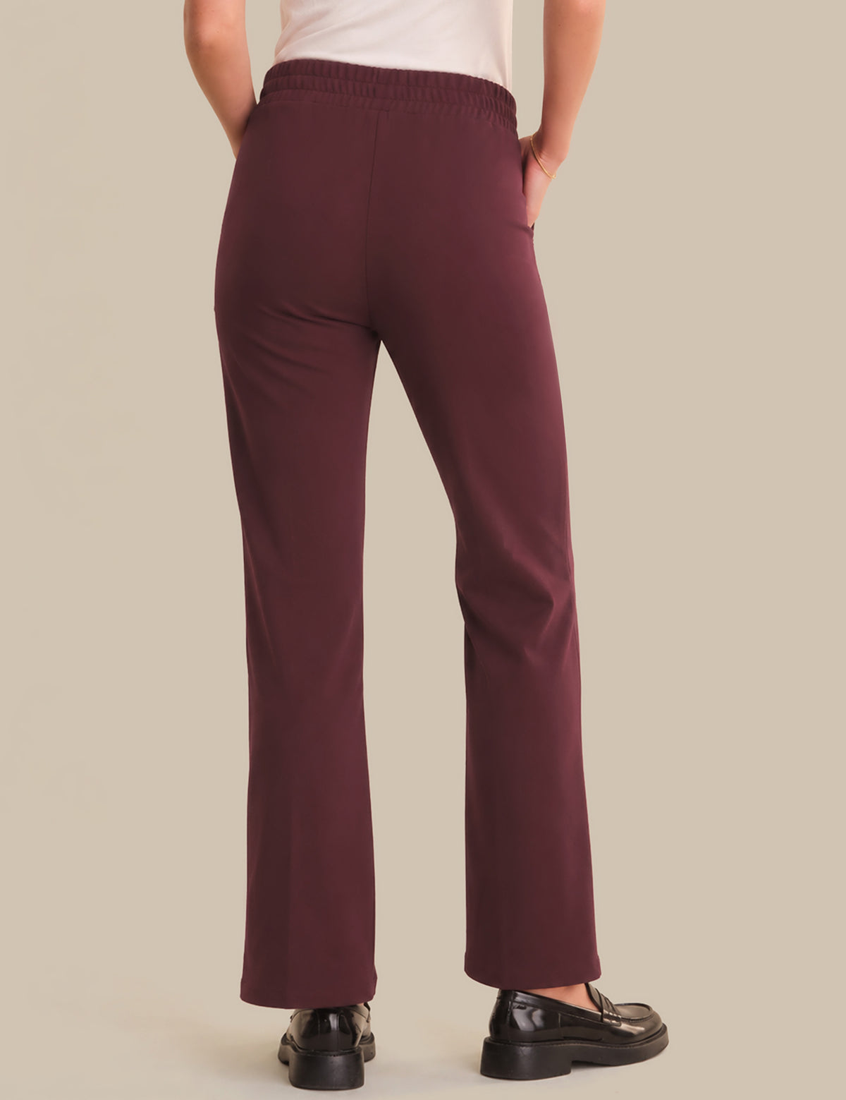 Maroon pants worn by a person on a beige background