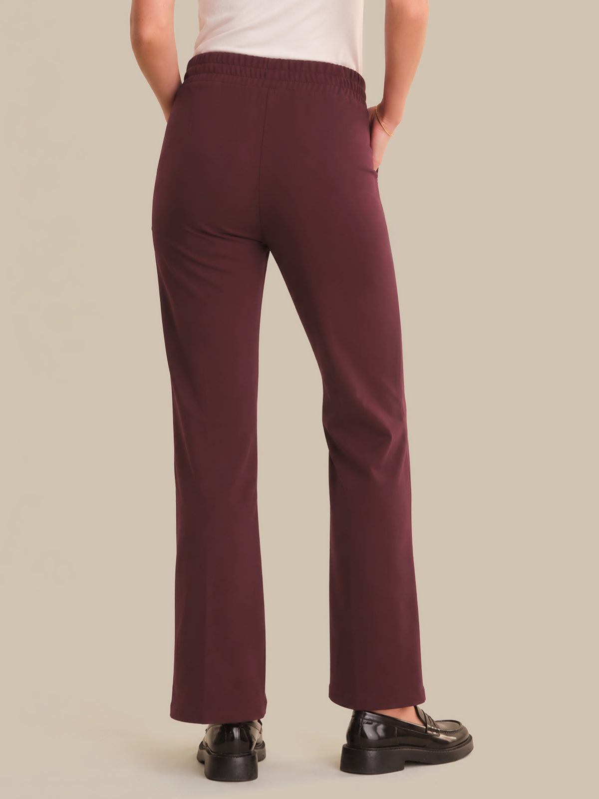 Maroon pants worn by a person on a beige background