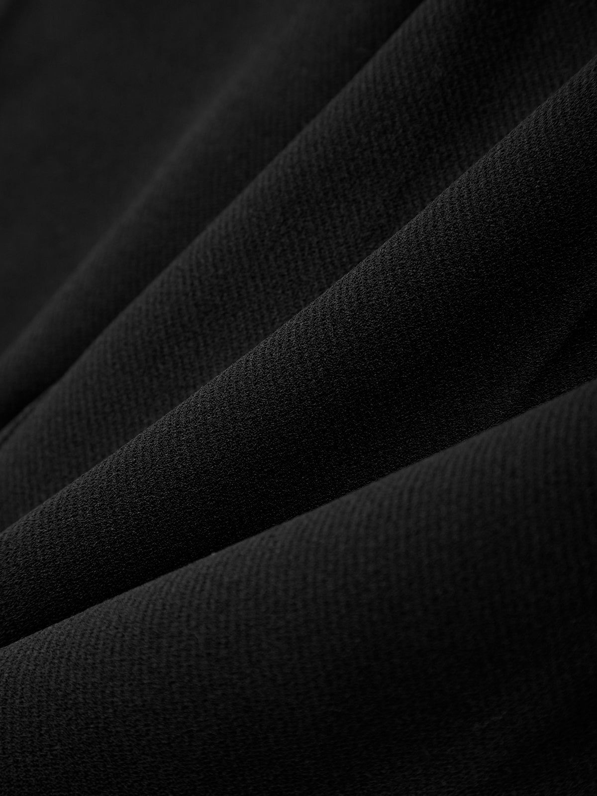 Close-up of black fabric with folds on a dark background