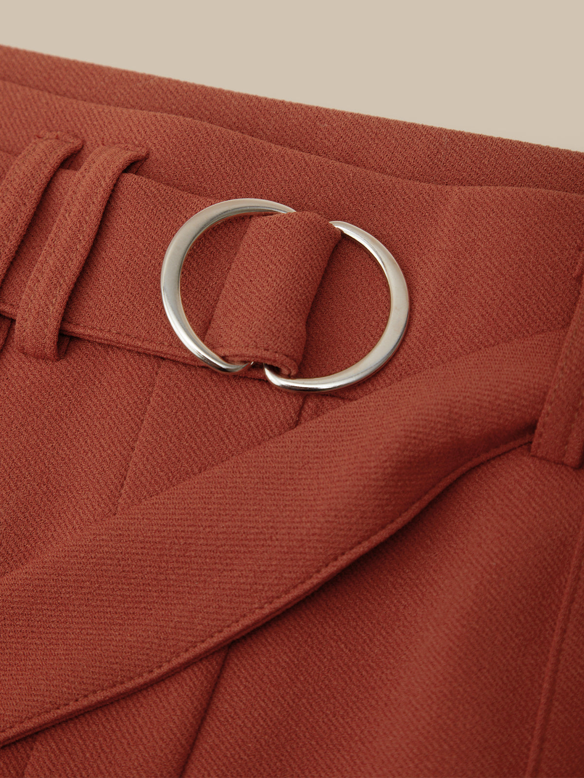 Close-up of a red belt with a silver buckle on a beige background