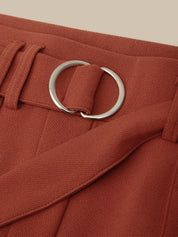 Close-up of a red belt with a silver buckle on a beige background