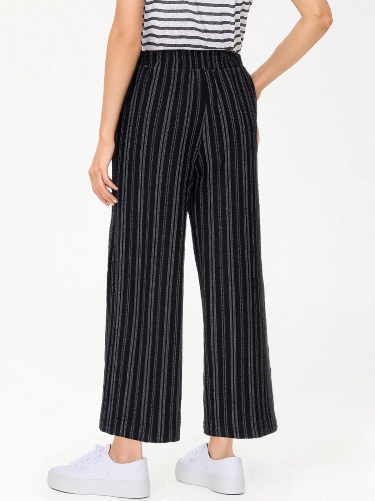 Person wearing black pinstripe pants with a white background