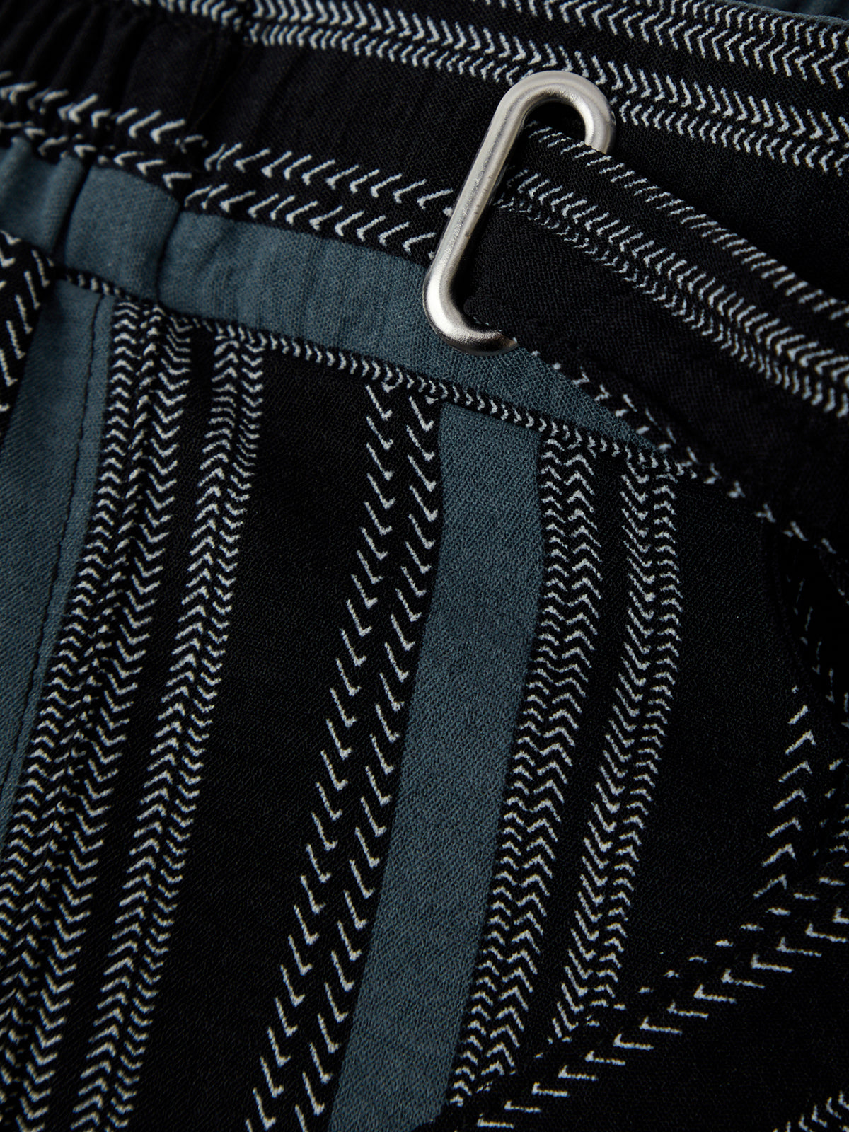 Close-up of a textured fabric with a metal clip on a black background