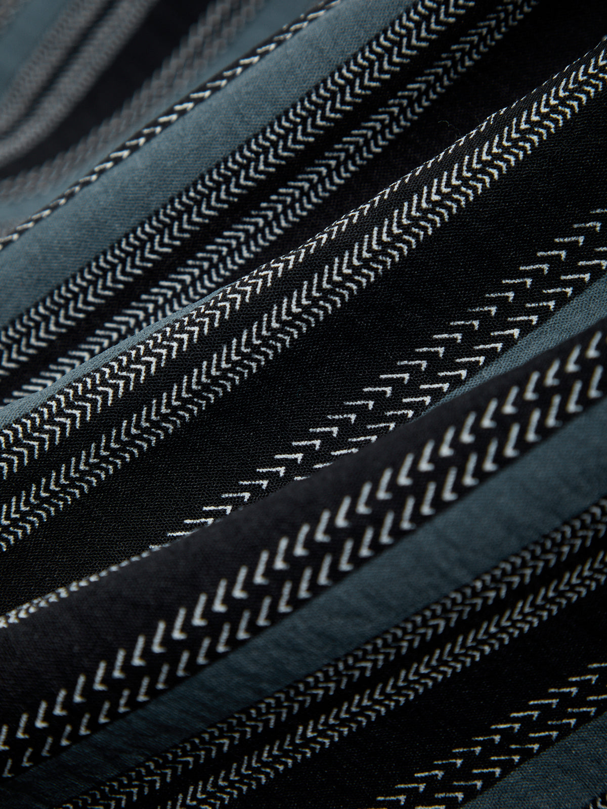 Close-up of a textured fabric with a pattern of raised lines on a dark background.