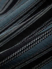 Close-up of a textured fabric with a pattern of raised lines on a dark background.