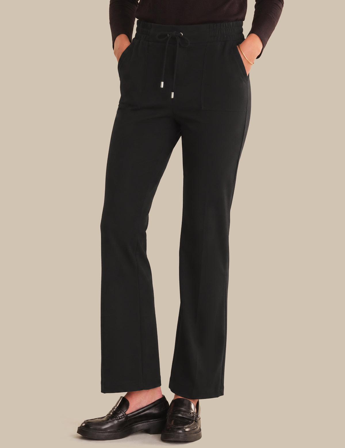 Person wearing black pants on a beige background