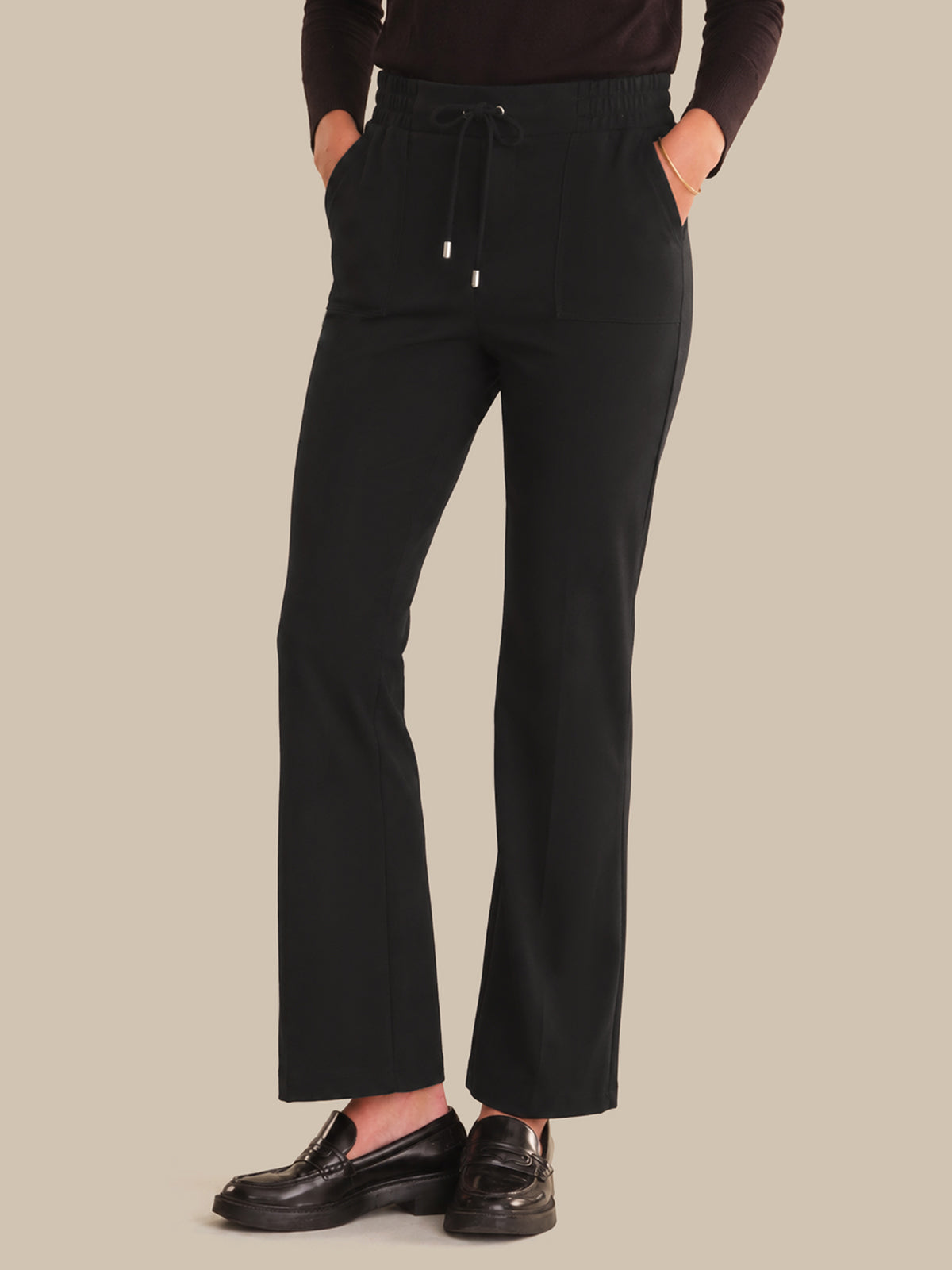 Person wearing black pants on a beige background