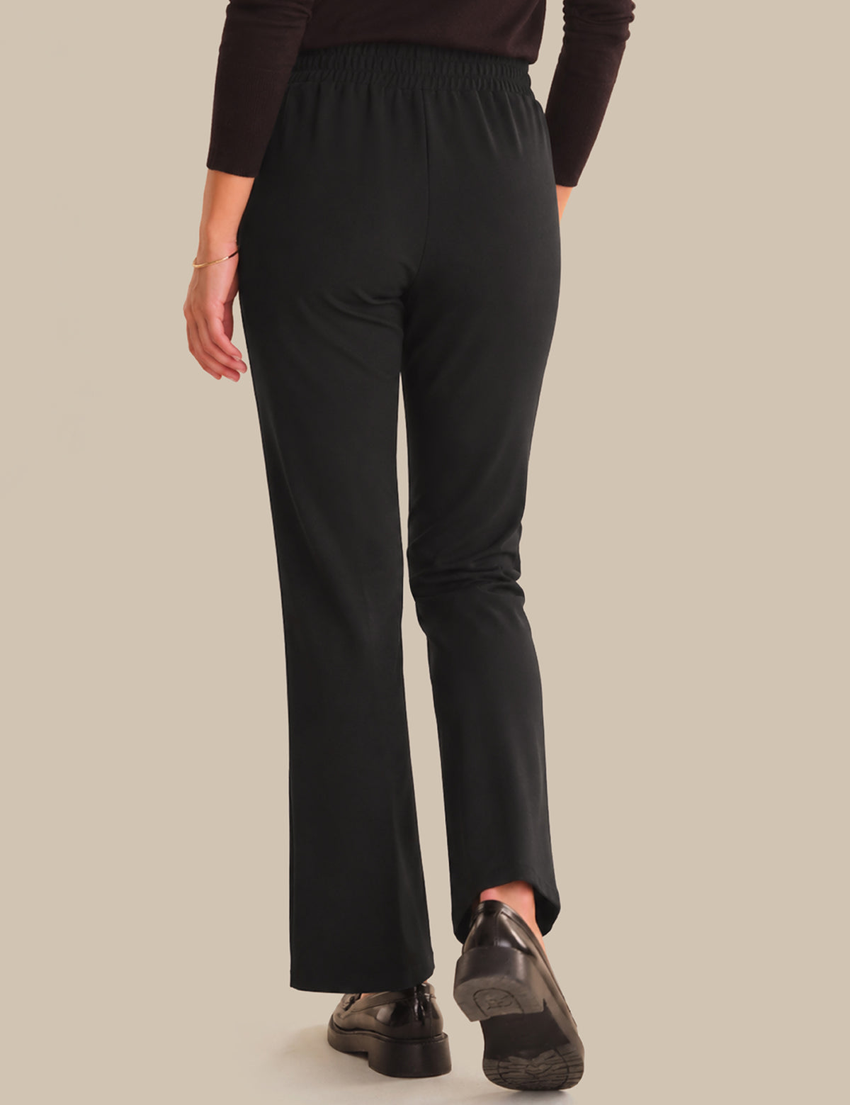 Person wearing black pants on a beige background