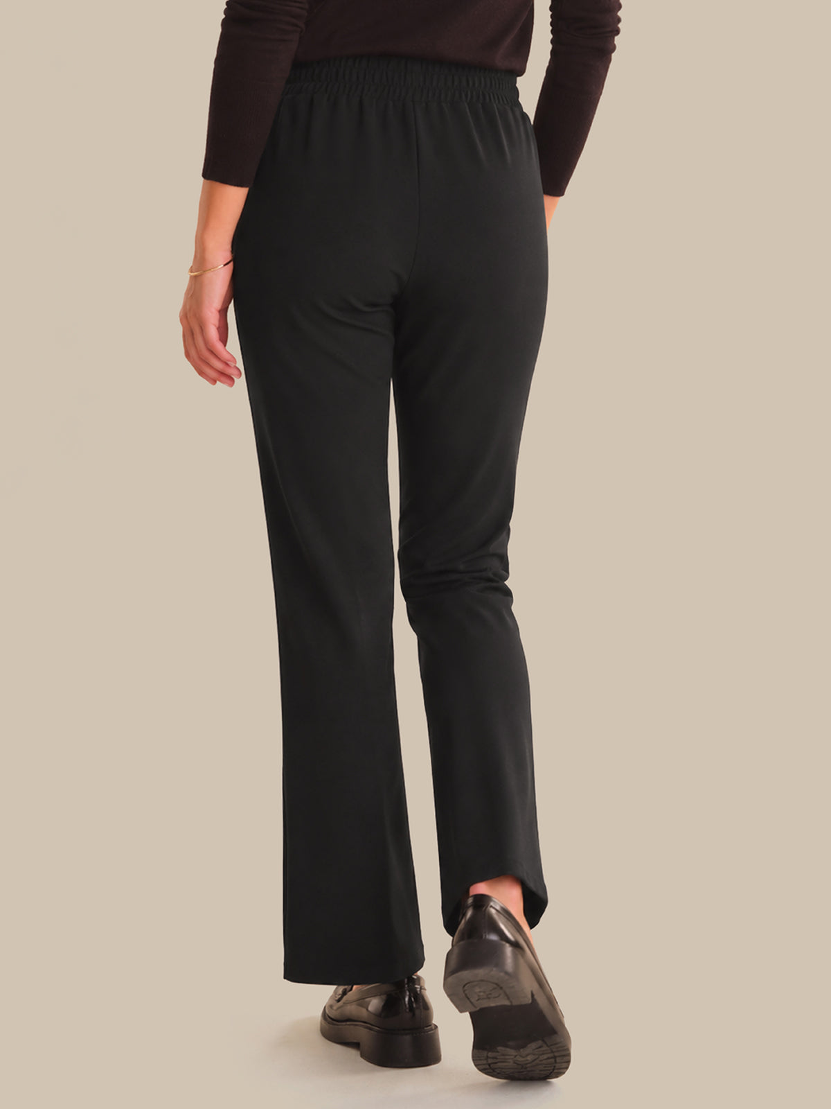 Person wearing black pants on a beige background