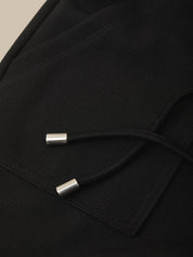Close-up of a black garment with silver buttons on a beige background