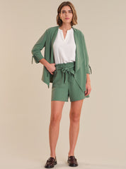 Woman wearing a green outfit with a white top on a beige background