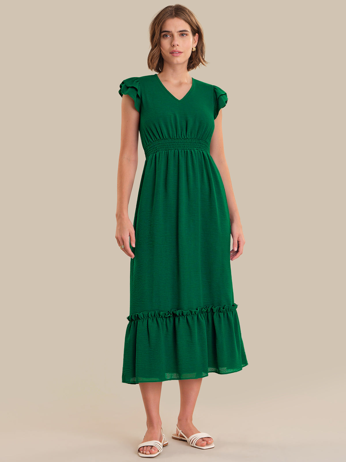 Woman wearing a green dress on a beige background