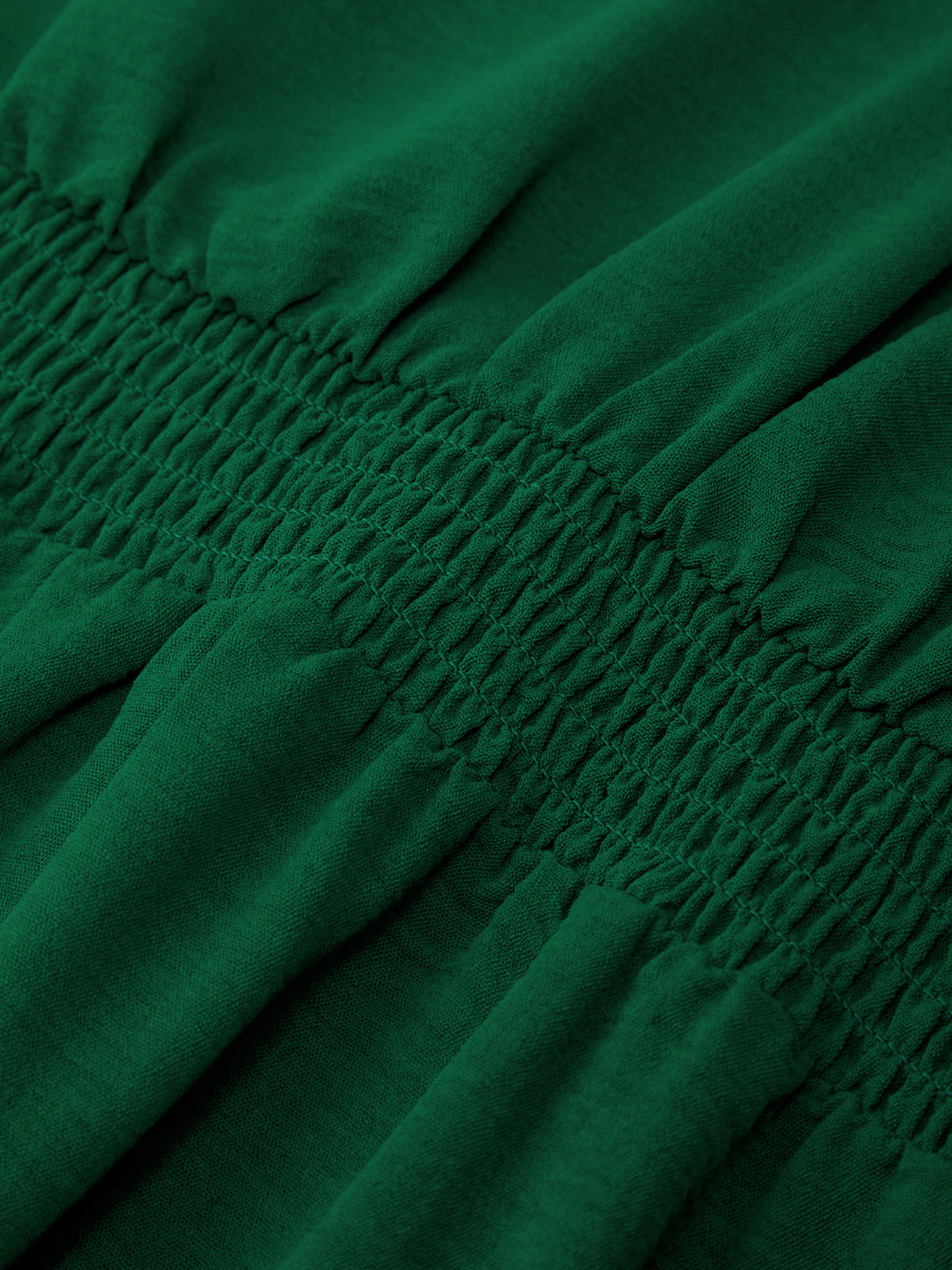 Close-up of green fabric with smocked waistband