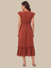 A woman shown from the back wearing a rust-colored midi dress with ruffled cap sleeves, a smocked waist, and a ruffled hem, paired with beige high-heeled sandals against a solid beige background.
