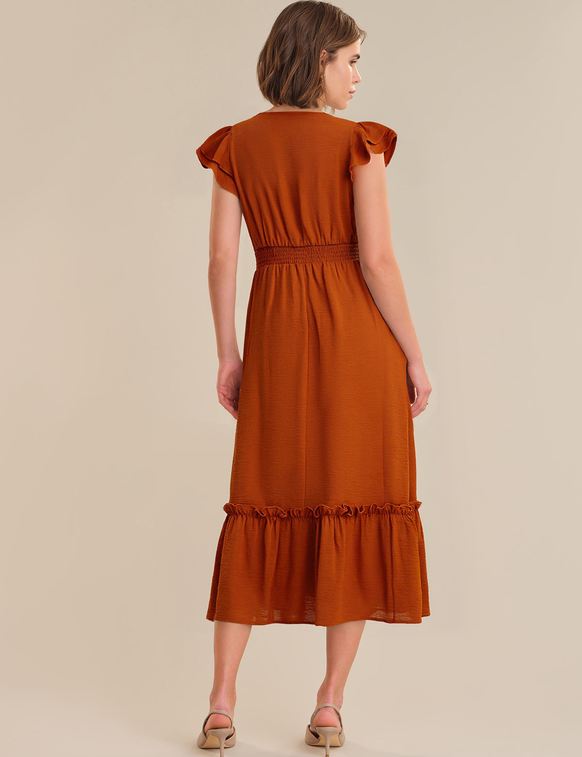 Woman wearing a rust-colored dress on a beige background