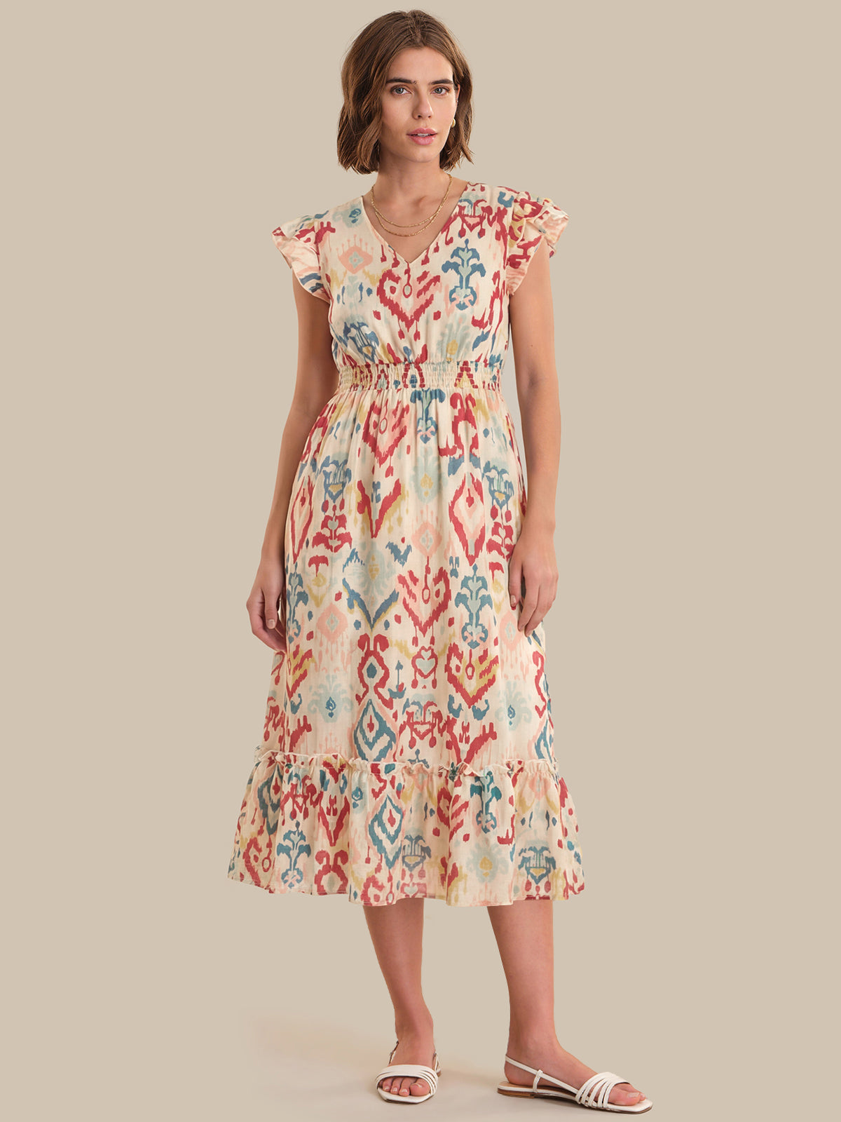 Woman wearing a colorful patterned dress on a beige background