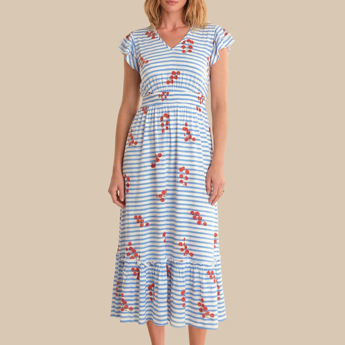 Woman wearing a blue and white striped dress with red floral patterns on a beige background