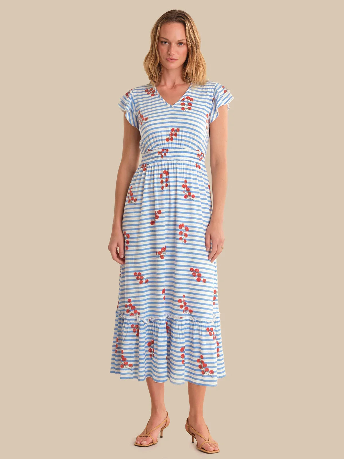 Woman wearing a blue and white striped dress with red floral patterns on a beige background