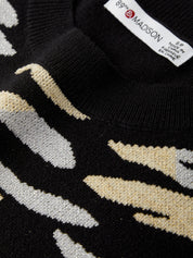 Close-up of a black sweater with beige and white pattern, featuring a brand label.