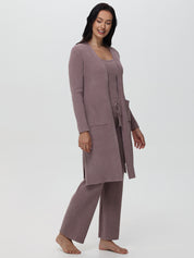 Woman wearing a long mauve cardigan and matching pants on a white background