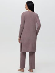 Person wearing a long mauve cardigan and pants on a white background