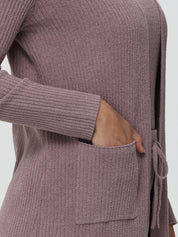 Close-up of a person wearing a ribbed knit cardigan with a pocket on a white background
