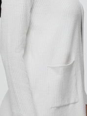 Close-up of a textured white sweater with a pocket on a light gray background