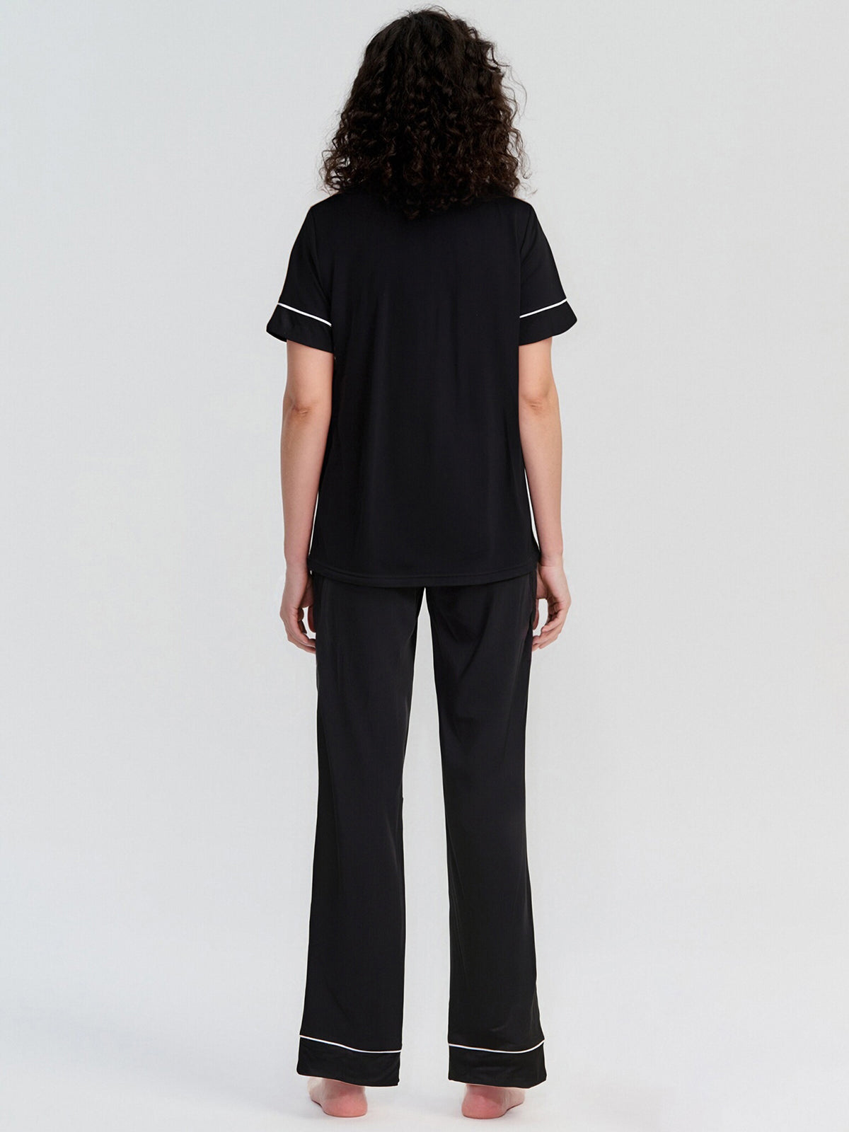 Person wearing a black pajama set with white trim on a white background