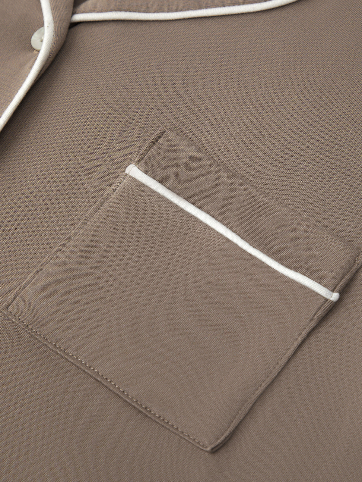 Close-up of a brown jacket with a pocket and white trim.