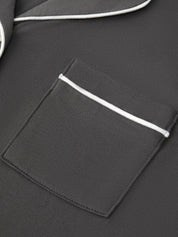 Close-up of a dark gray fabric garment featuring a pocket with a contrasting white piping trim.