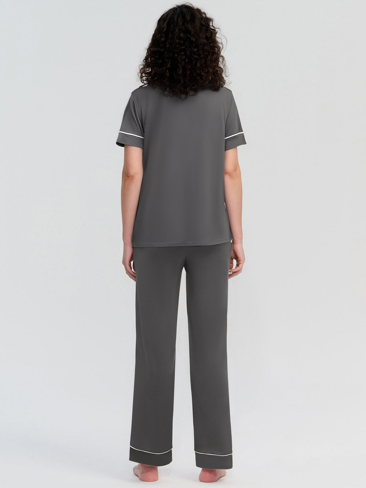 Person wearing gray pajamas with white trim on a light gray background