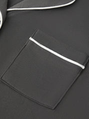 Close-up of a dark gray jacket with a pocket and white piping detail.