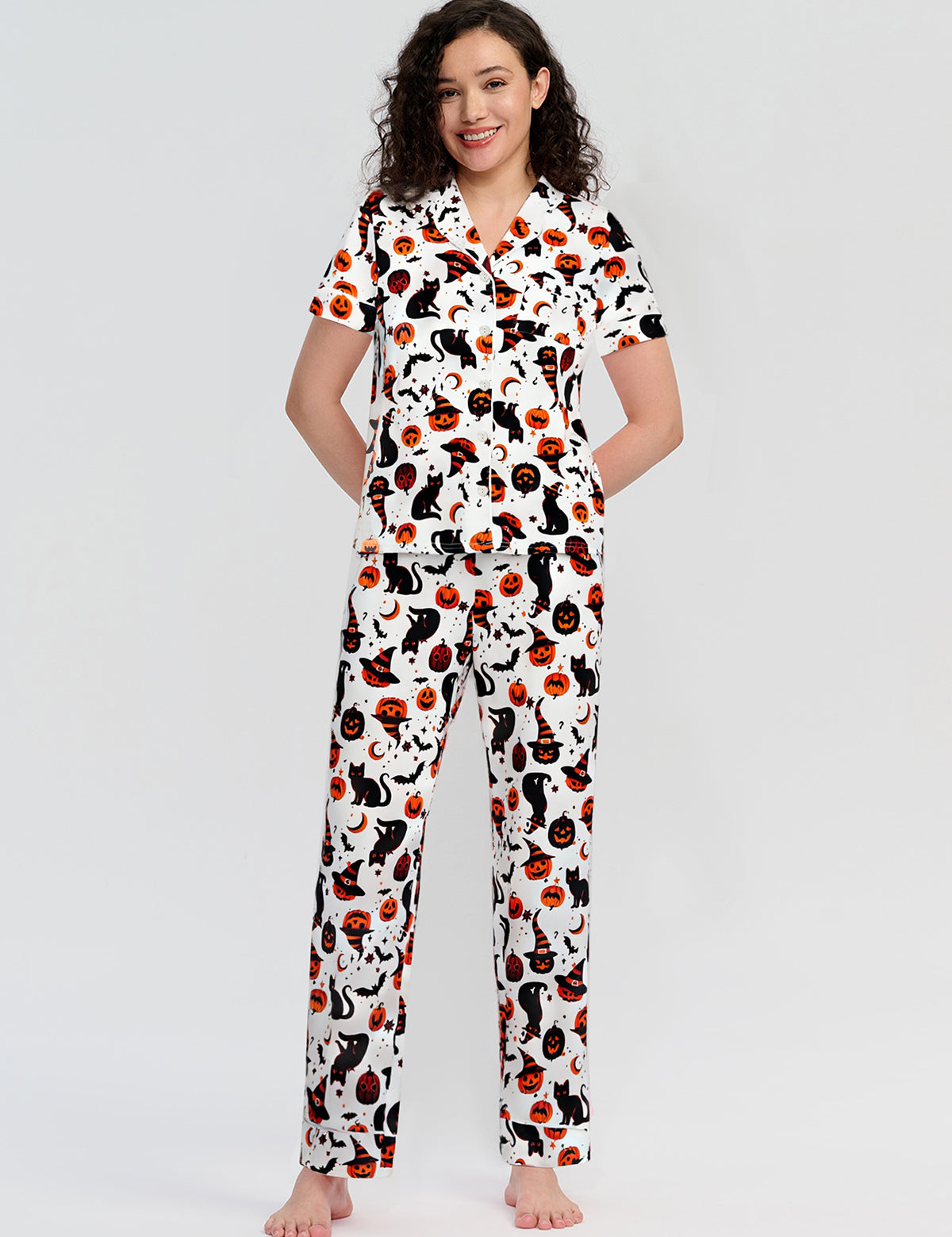 Woman wearing a pajama set with cat and pumpkin pattern on a white background