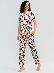 Woman wearing a pajama set with a cat and pumpkin pattern on a white background