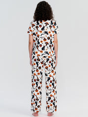 Person wearing a pajama set with a cat and pumpkin pattern on a white background