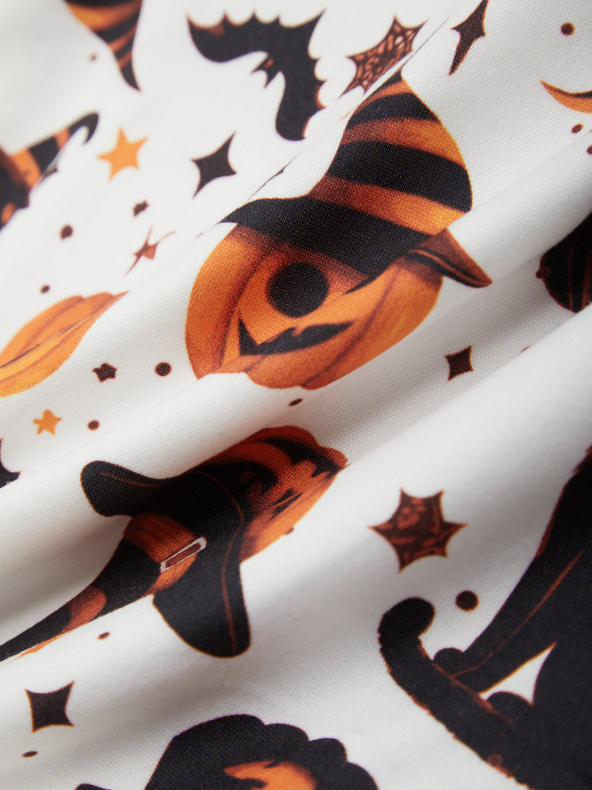 Halloween-themed fabric with pumpkins, cats, and stars on a white background