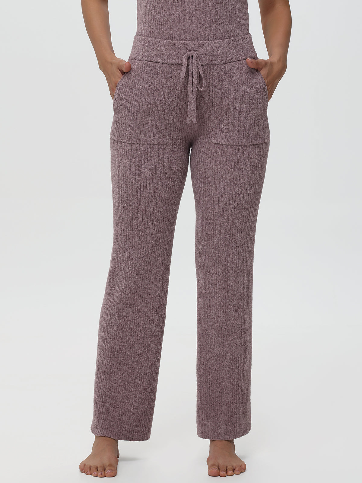 Person wearing a pair of purple pajama pants on a white background