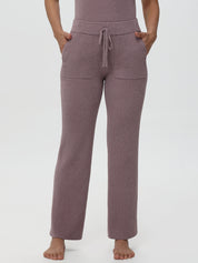 Person wearing a pair of purple pajama pants on a white background