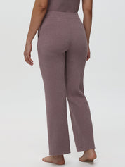 Person wearing ribbed mauve pants on a white background