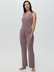 Woman wearing a mauve sleeveless top and pants on a white background