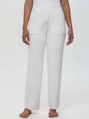 White ribbed knit pants worn by a person on a white background