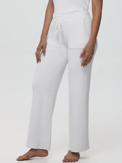 White ribbed lounge pants worn by a person on a white background