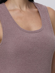 Close-up of a person wearing a textured mauve tank top against a neutral background