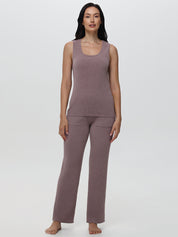 Woman wearing a mauve sleeveless top and pants on a white background