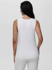 Woman wearing a white sleeveless top against a plain background