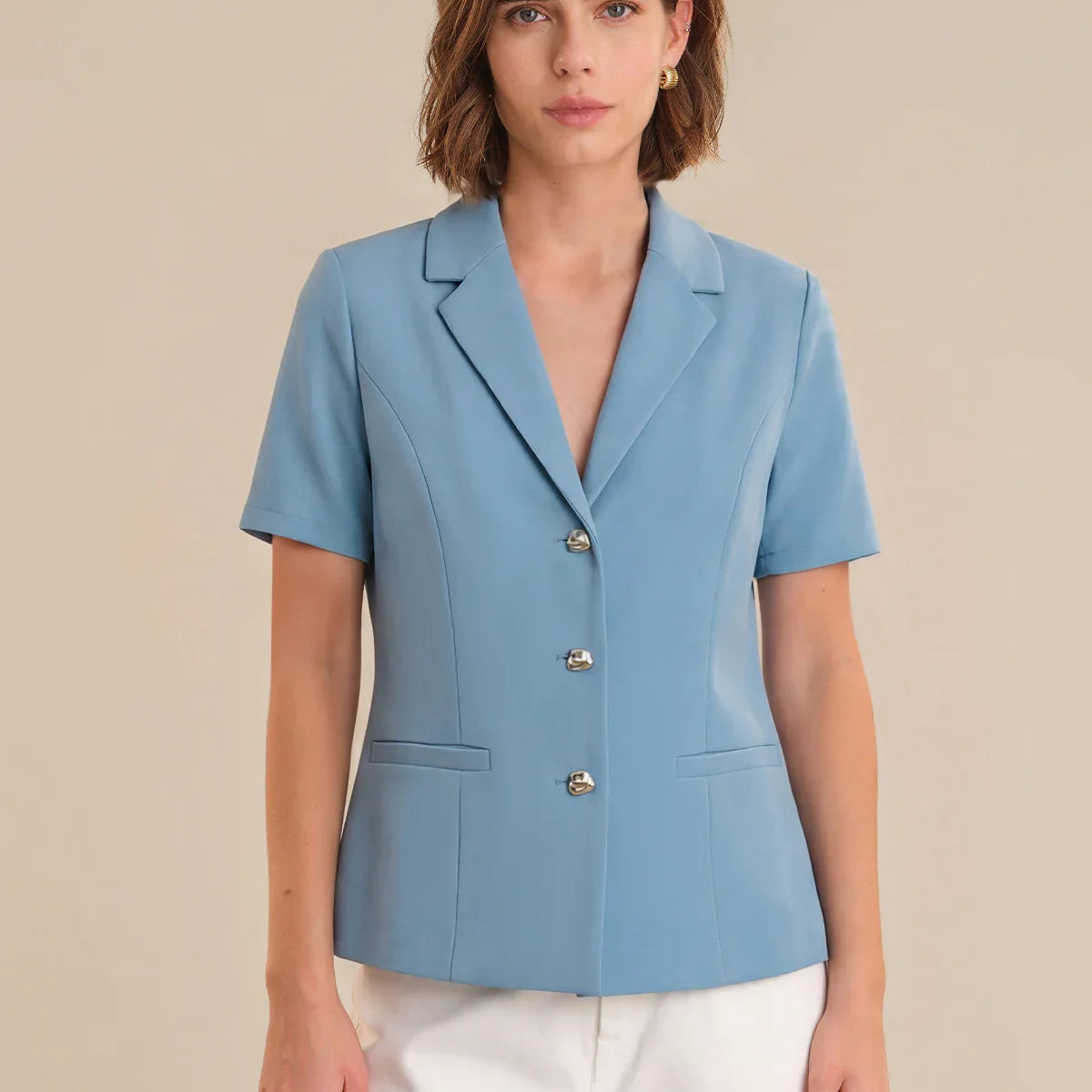 Woman wearing a light blue blazer with short sleeves on a beige background