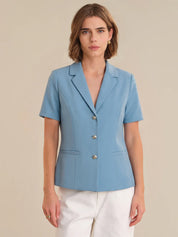 Woman wearing a light blue blazer with short sleeves on a beige background