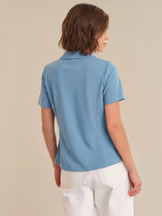 Person wearing a light blue polo shirt and white pants on a beige background