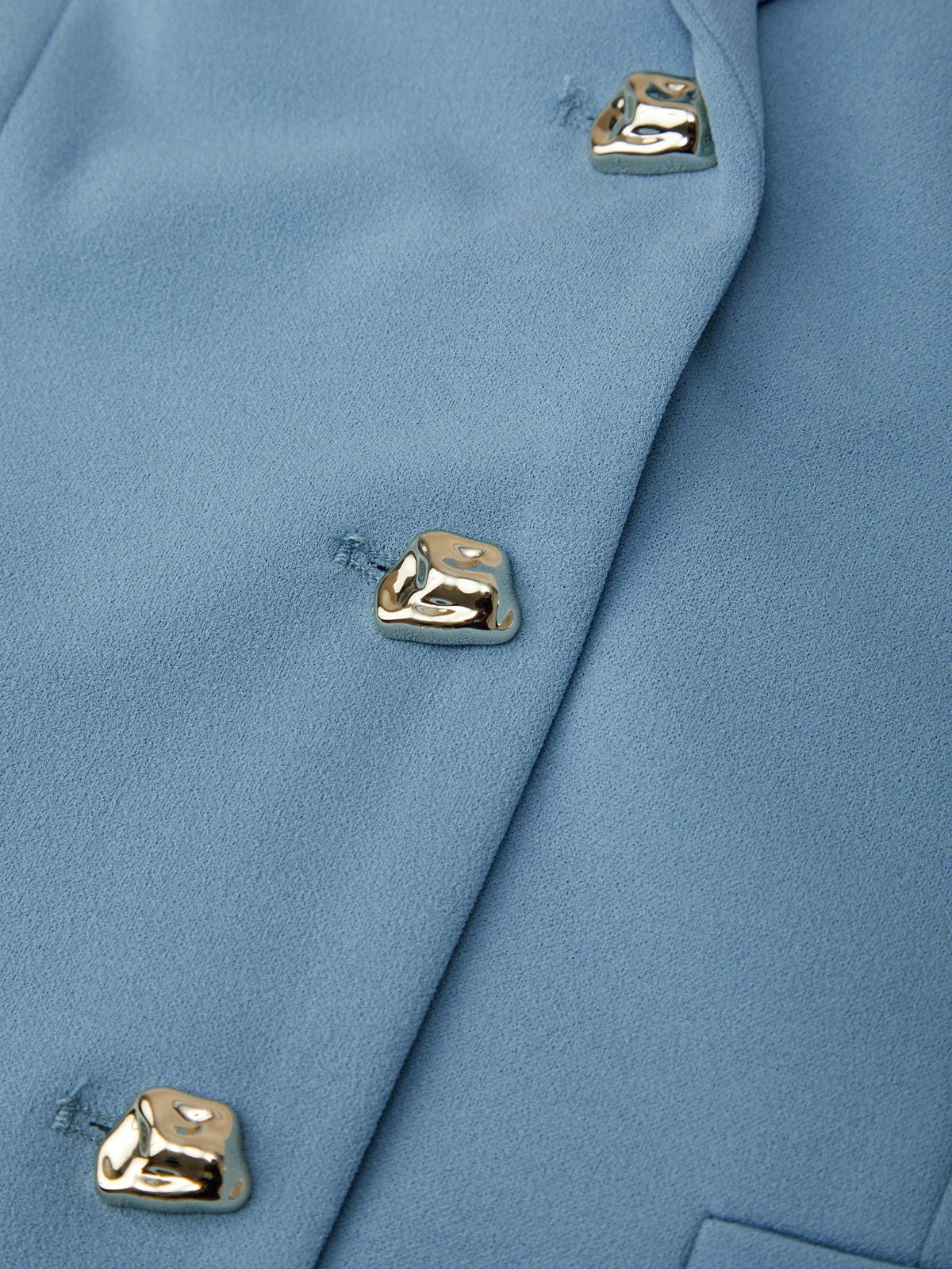 Close-up of a blue coat with gold buttons on a matching background
